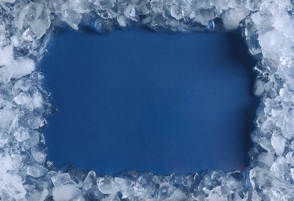 Frame of crushed ice on blue background, top view. Space for text