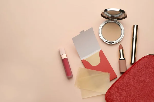 Flat lay composition with facial oil blotting tissues and makeup products on beige background, space for text. Mattifying wipes