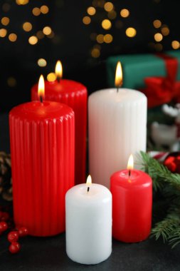 Bulanık Noel ışıklarına karşı karanlık masada yanan mumlar ve şenlikli dekor.