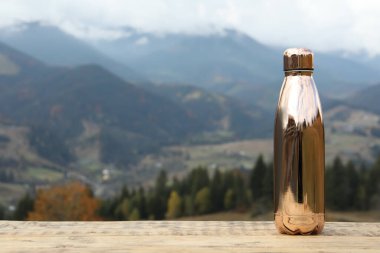 Dağ manzarasına karşı ahşap masadaki termos. Metin için boşluk