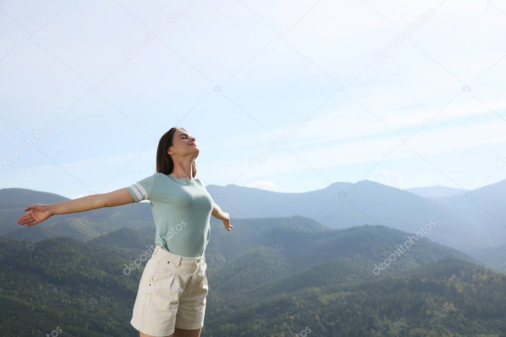 Beautiful young woman in peaceful mountains on sunny day. Feeling freedom