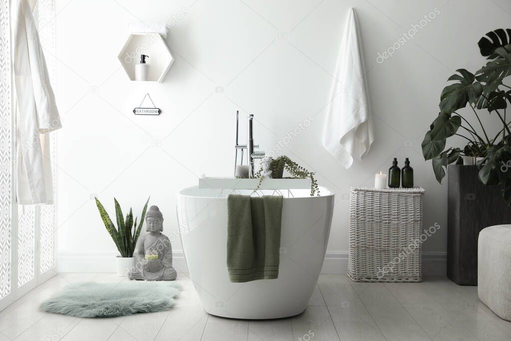 Stylish bathroom interior with modern tub, houseplants and beautiful decor. Home design