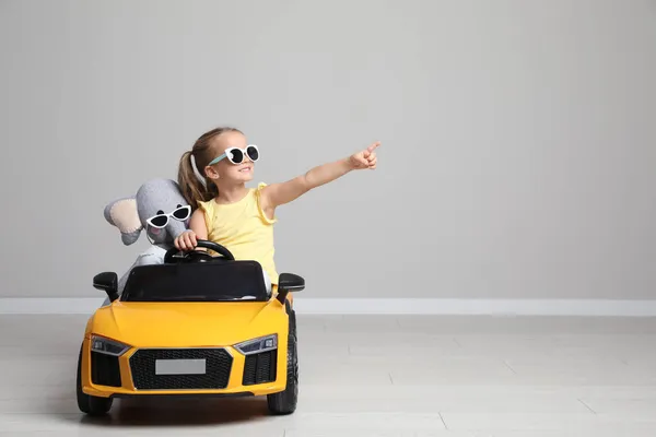 Cute Little Girl Toy Elephant Driving Children Car Grey Wall — Stock Photo, Image