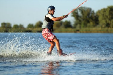 Genç çocuk nehirde wakeboard yapıyor. Aşırı su sporu