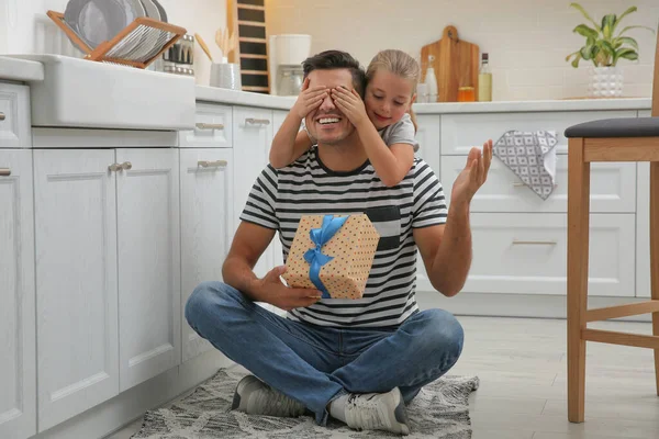 Man receiving gift for Father\'s Day from his daughter in kitchen