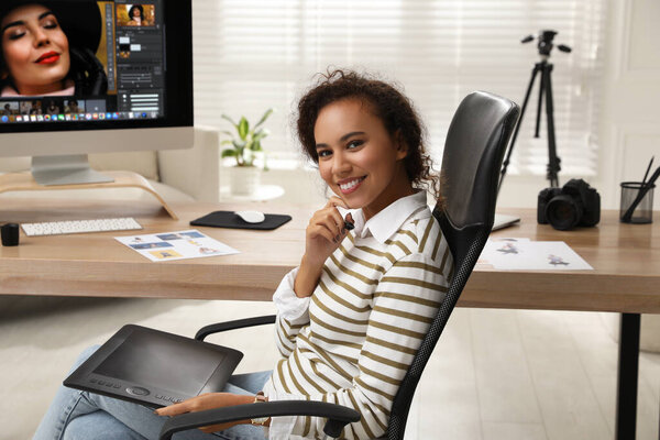 Professional African American retoucher working with graphic tablet at desk in office