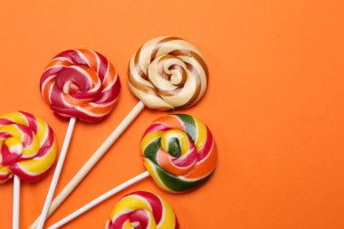 Tatlı lolipoplar turuncu arka planda, düz yerde. Metin için boşluk