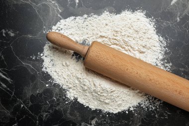 Siyah mermer masa üzerinde ahşap oklu iğne ve un, üst manzara.