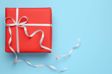 Açık mavi arka planda beyaz fiyonklu güzel bir hediye kutusu, üst manzara. Metin için boşluk