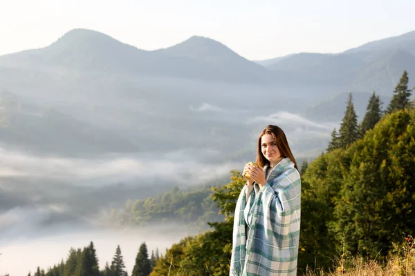 山の中で熱い飲み物のカップを楽しんで居心地の良いプレイを持つ女性 — ストック写真