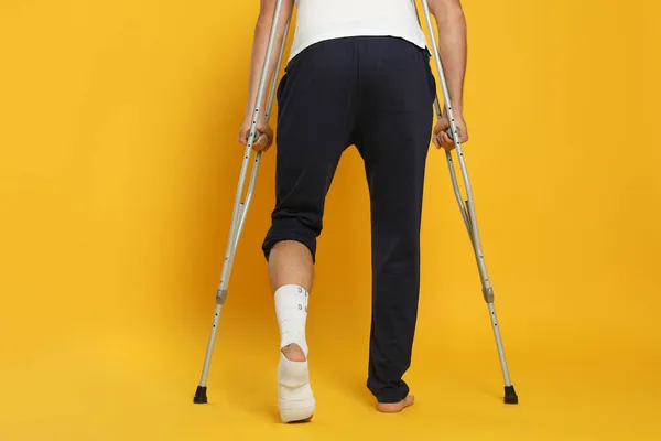 Mann Mit Verletztem Bein Mit Krücken Auf Gelbem Hintergrund Nahaufnahme — Stockfoto