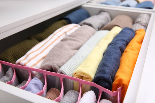 Открытый ящик со сложенной одеждой внутри, крупным планом. Вертикальное хранение