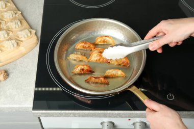 Mutfakta kızgın yağlı tavada gyoza pişiren kadın, yakın plan.