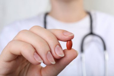 Doktor kırmızı hap tutuyor, yakın plan. Anemi kavramı