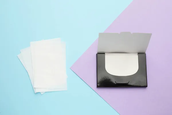 Package with facial oil blotting tissues on color background, flat lay. Mattifying wipes