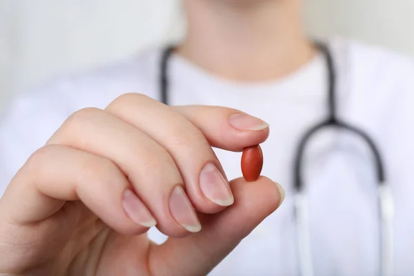 Doctor holding red pill, closeup. Anemia concept