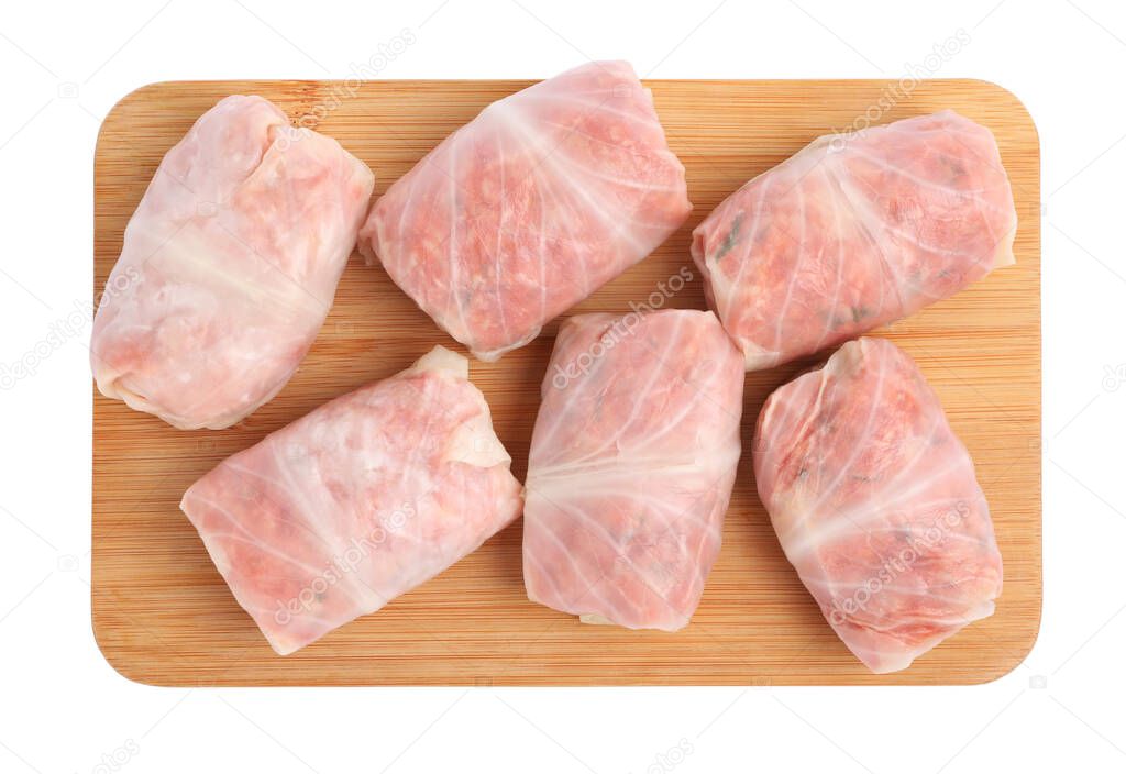 Wooden board with uncooked stuffed cabbage rolls on white background, top view
