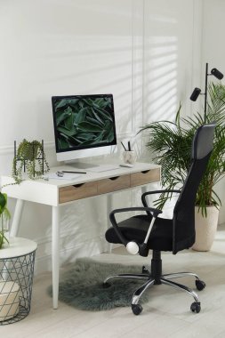 Modern bilgisayar ve yeşil bitkilerle dolu rahat bir iş yeri. İç tasarım