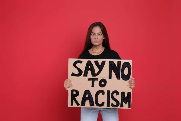 拿着标语牌的年轻妇女在红色背景下对种族主义说不 — 图库照片