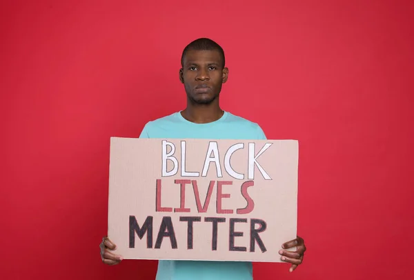 African American man holding sign with phrase Black Lives Matter on red background. End racism