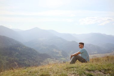 İnsan güneşli bir günde güzel dağ manzarasının tadını çıkarıyor.