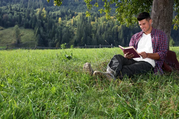Красивый Человек Читает Книгу Деревом Зеленом Лугу Рядом Лесом — стоковое фото
