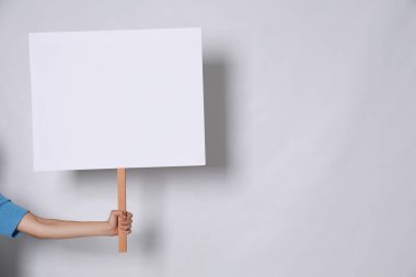 Açık gri arka planda boş tabela tutan kadın, yakın plan. Metin için boşluk
