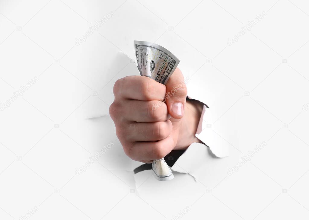 Man breaking through white paper with money in fist, closeup