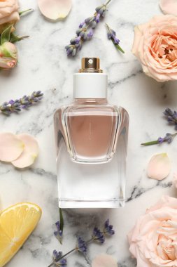 Düz kompozisyon, beyaz mermer masa üzerinde parfüm şişesi ve taze narenciye meyvesi.