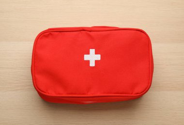 First aid kit bag on wooden table, top view. Health care clipart