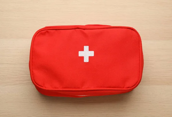 First aid kit bag on wooden table, top view. Health care