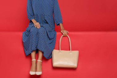 Kırmızı arka planda şık çantalı bir kadın, yakın plan. Metin için boşluk