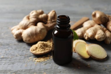 Şişedeki zencefil yağı açık gri masada.