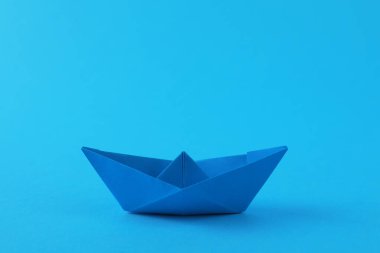 Açık mavi arka planda el yapımı kağıt tekne. Origami sanatı