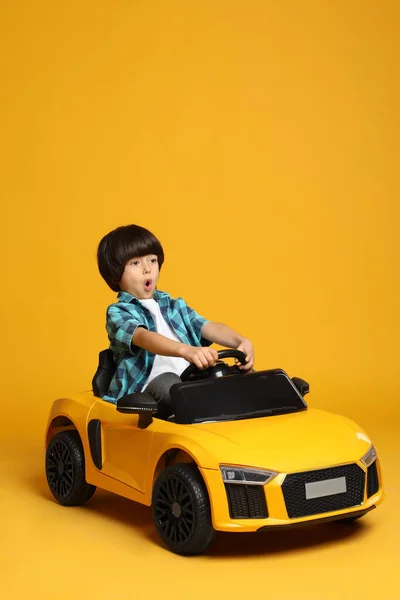 Cute Little Boy Driving Children Electric Toy Car Yellow Background — Stock Photo, Image