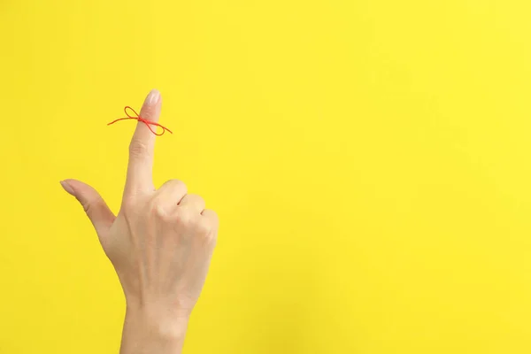 女性的食指上绑着红色的蝴蝶结 作为黄色背景的提醒 案文的篇幅 — 图库照片