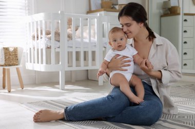 Bebek odasında bebeğiyle mutlu genç bir anne. Metin için boşluk