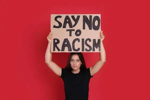拿着标语牌的年轻妇女在红色背景下对种族主义说不 — 图库照片