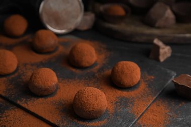 Lezzetli çikolatalı trüf mantarı. Siyah masaya kakao sürülmüş. Yakın plan.