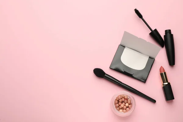 Flat lay composition with facial oil blotting tissues and makeup products on pink background, space for text. Mattifying wipes