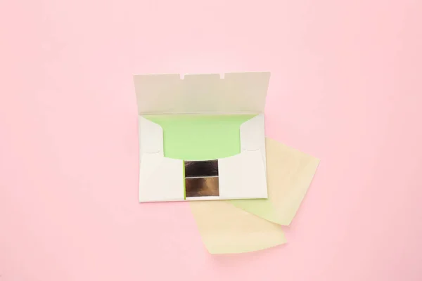 Package with facial oil blotting tissues on pink background, flat lay. Mattifying wipes