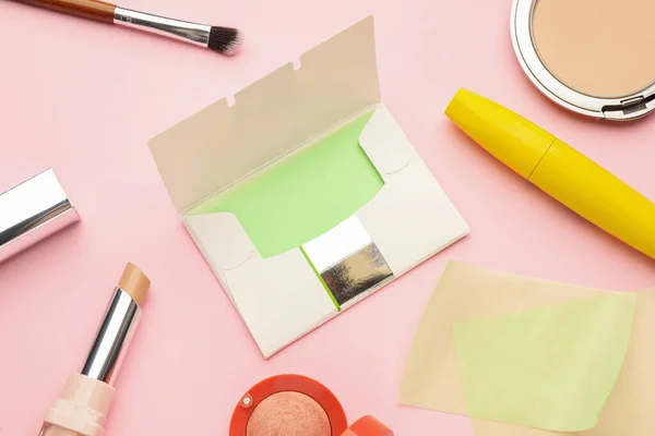 Flat lay composition with facial oil blotting tissues and makeup products on pink background. Mattifying wipes