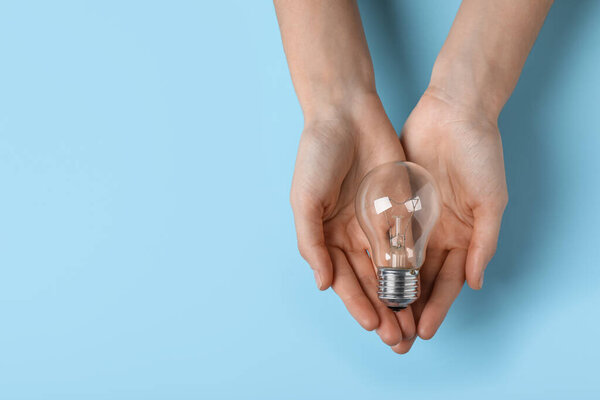 Woman holding light bulb on color background, top view. Space for text