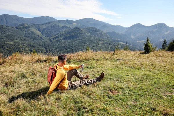 魔法瓶やバックパック付きの観光客は美しい山の風景を楽しむ — ストック写真