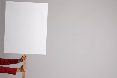 Açık gri arka planda boş tabela tutan kadın, yakın plan. Tasarım için boşluk