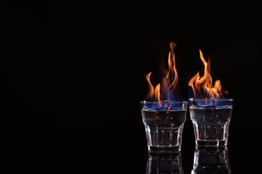 Siyah arka planda shot bardaklarında yanan votka, metin için yer