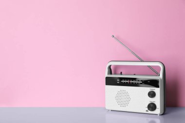 Retro radyo alıcısı pembe arka planda masanın üzerinde. Metin için boşluk