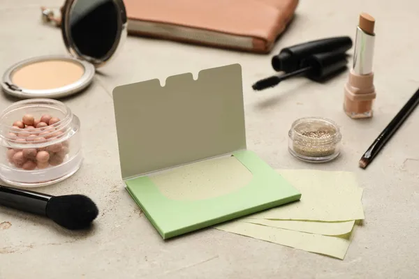Facial oil blotting tissues and different decorative cosmetics on light grey background. Mattifying wipes