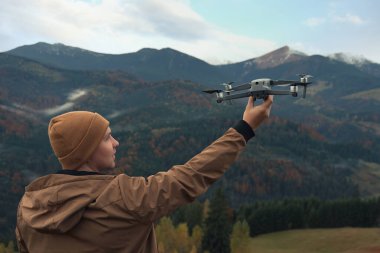 Dağlarda modern drone 'u olan genç bir adam.