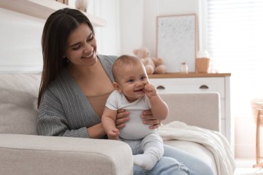 Oturma odasında tatlı bebeğiyle mutlu genç bir anne.